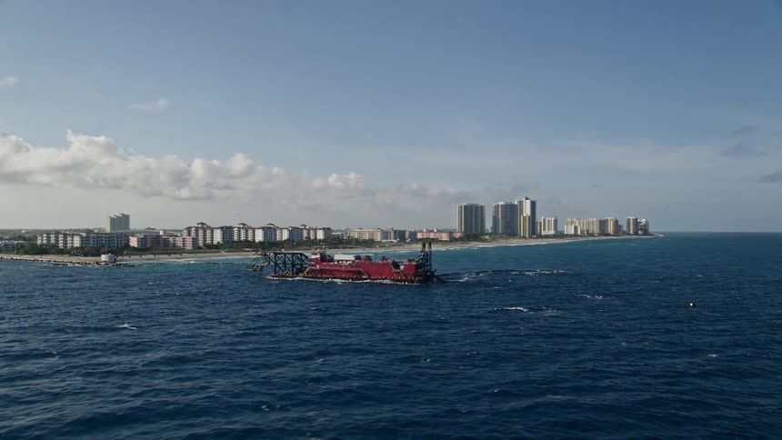 Aerial footage of a dredging ship navigating the coast of Palm Beach Shores Florida