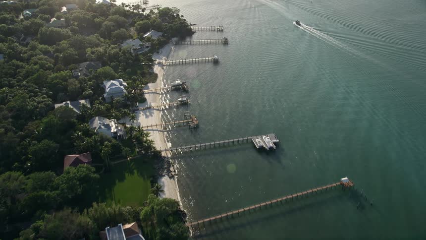 Flying over docks and waterfront properties at dusk approaching residential neighborhoods and shorelines in Saint Lucie Inlet Stuart FL