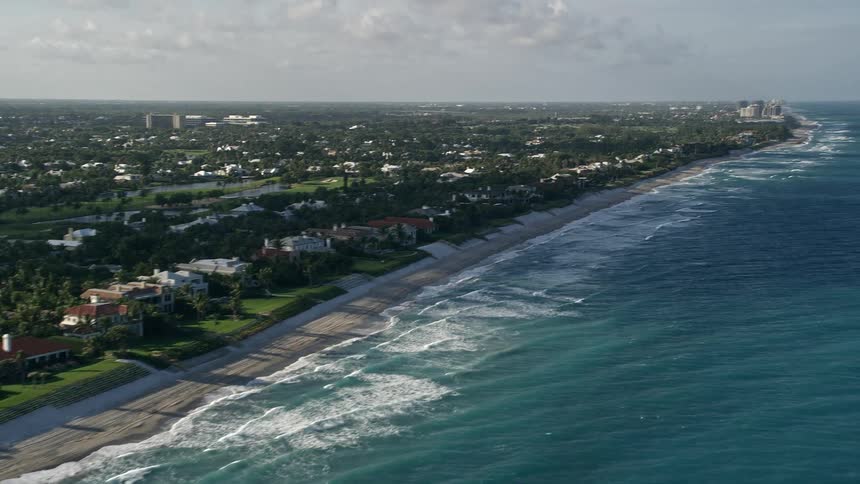 Aerial view of North Palm Beach coastline with residential homes and people enjoying the beach on a partly cloudy day
