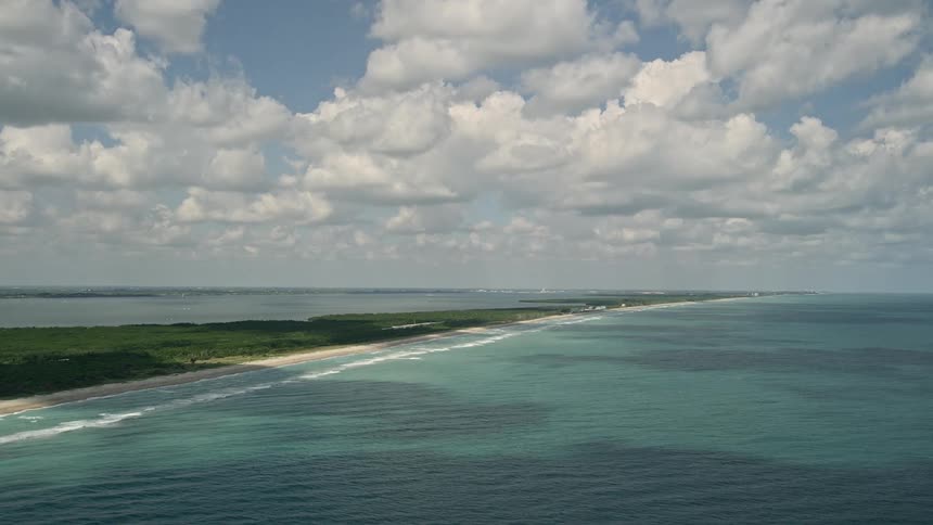 Aerial view of Fort Pierce coastline as the camera follows the blue ocean waters on a partly cloudy day