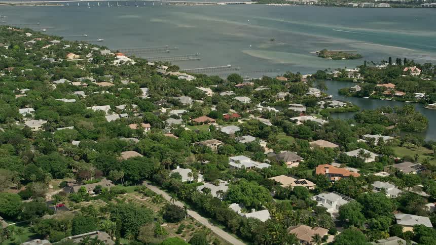 Flying over a riverfront community in Stuart Florida with tropical houses and waterfront property on a sunny day