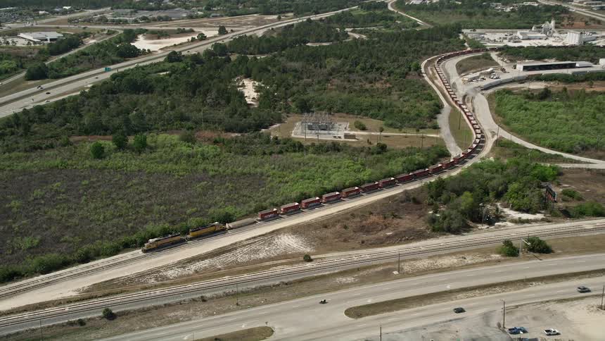 Approaching aerial footage of a stopped train in Cocoa Florida on a partly cloudy day