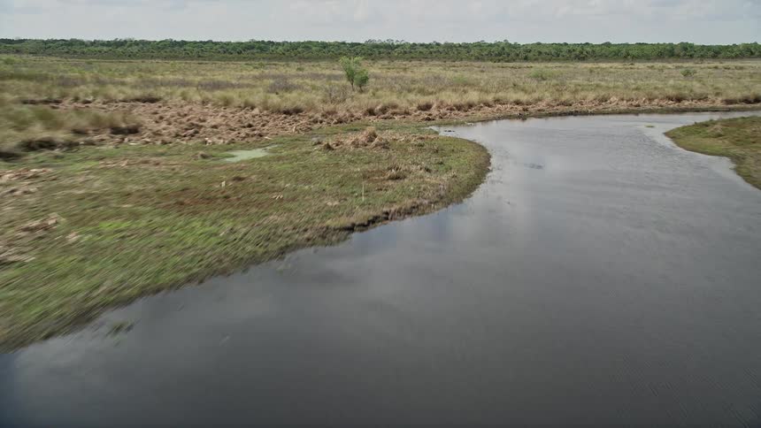 Low flying aerial footage over a river valley surrounded by wetlands and marshland captured on a partly cloudy day in Cocoa Florida