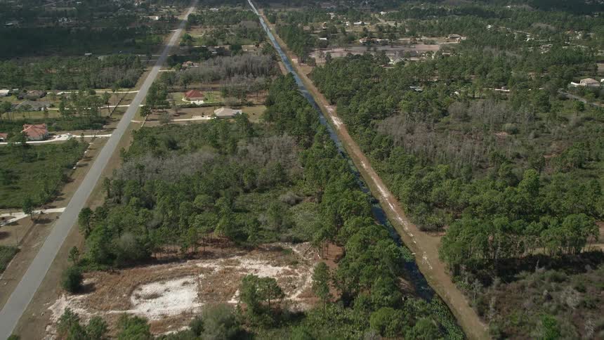 Aerial view of residential areas and trees in Wedgefield Florida with partly cloudy skies