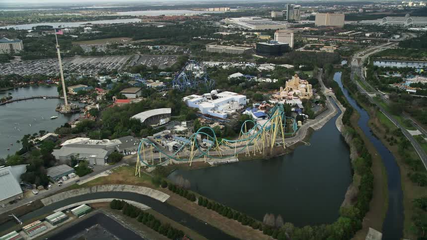 Aerial footage of Seaworld Orlando with a roller coaster and amusement park attractions surrounding multiple ponds