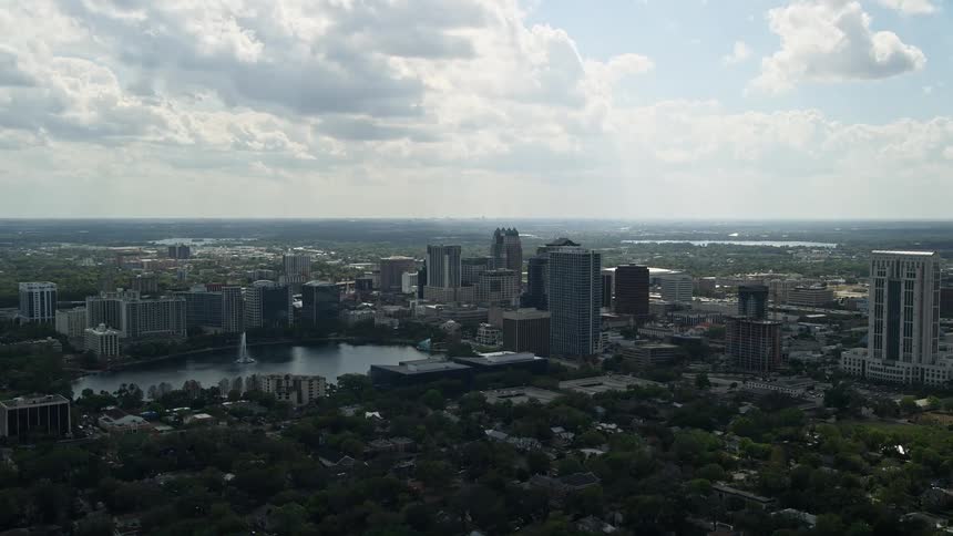 A stunning aerial view of Downtown Orlandos high-rise buildings around Lake Eola on a partly cloudy day