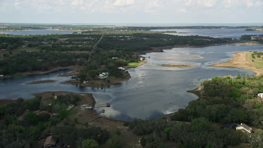 Aerial footage of homes on the shores of Lake Avalon Florida on a partly cloudy day showcasing lakefront and lakeside properties