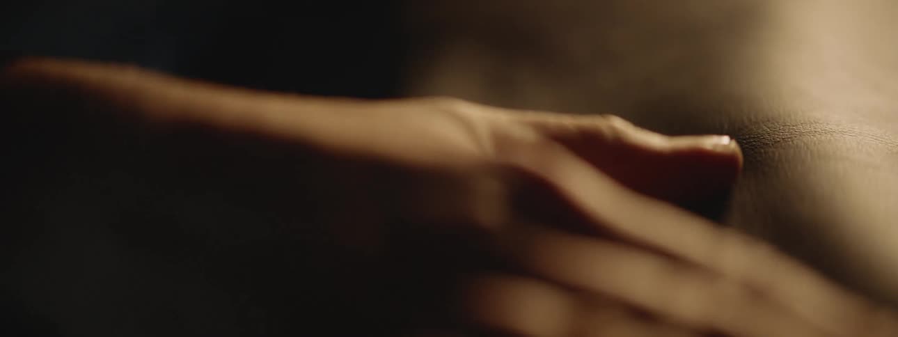 Close up of the hands of a craftsman using his hands to flatten a piece of leather over a table