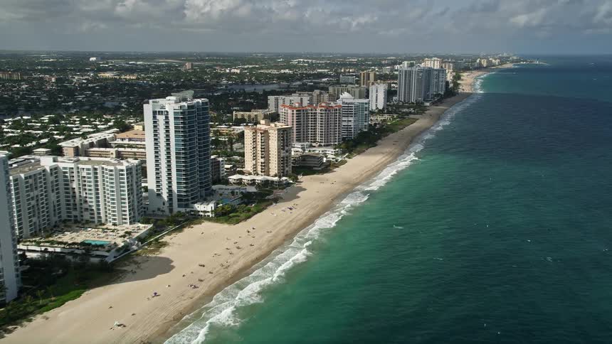 An aerial view of a beach with apartment complexes and coastline in Lauderdale by the Sea Florida during the day