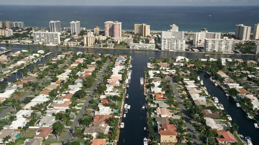 Flying over residential neighborhoods on canals in Pompano Beach Florida with a view of water bodies and waterfront properties