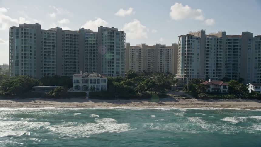 A breathtaking aerial view of condominium complexes on the beachfront of Highland Beach Florida with crystal clear waters and lively shoreline