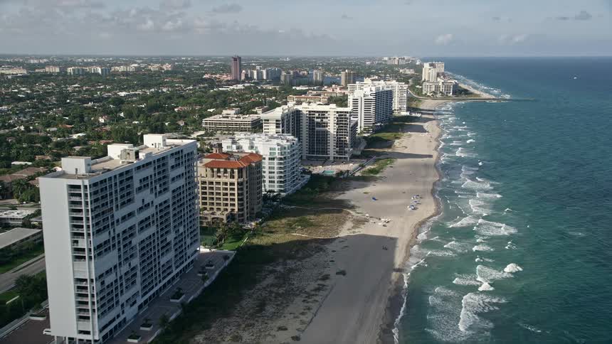 A breathtaking aerial shot of sunbathers on a beach in Boca Raton Florida with apartment buildings revealed as the camera approaches