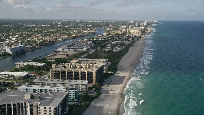 An aerial view of Hillsboro Beach in Florida with a reveal of the coastline and residential areas as the camera approaches from above