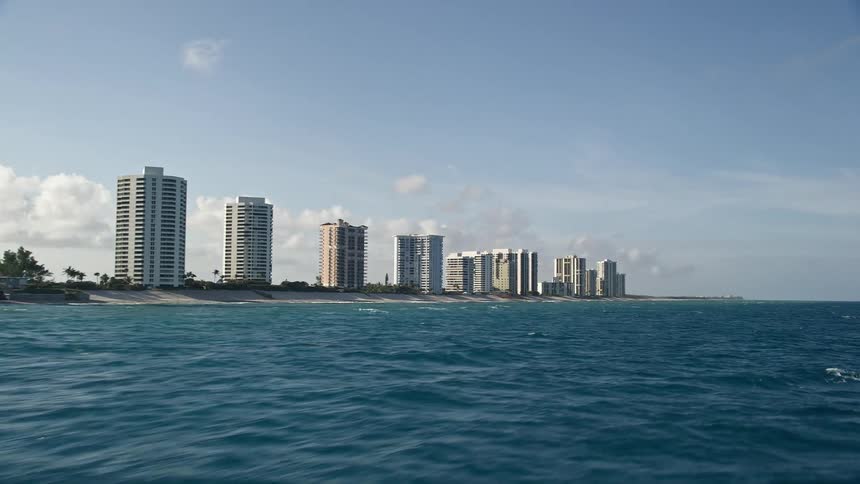 Aerial footage flyover of Riviera Beach Florida revealing the coastal condominiums and shoreline