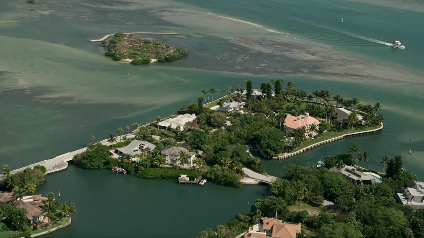 Fly over upscale homes situated on small islands in the Indian River of Stuart Florida during a partly cloudy day