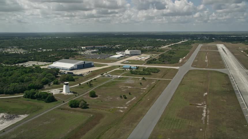 Aerial footage of a runway and hangar at Melbourne Regional Airport in Florida during daytime summer showing a road leading to the runways