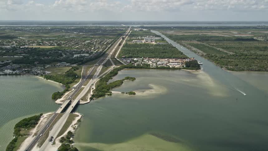 Aerial footage of a car approaching Merritt Island on the Bennett Causeway in Florida during daytime with partly cloudy skies