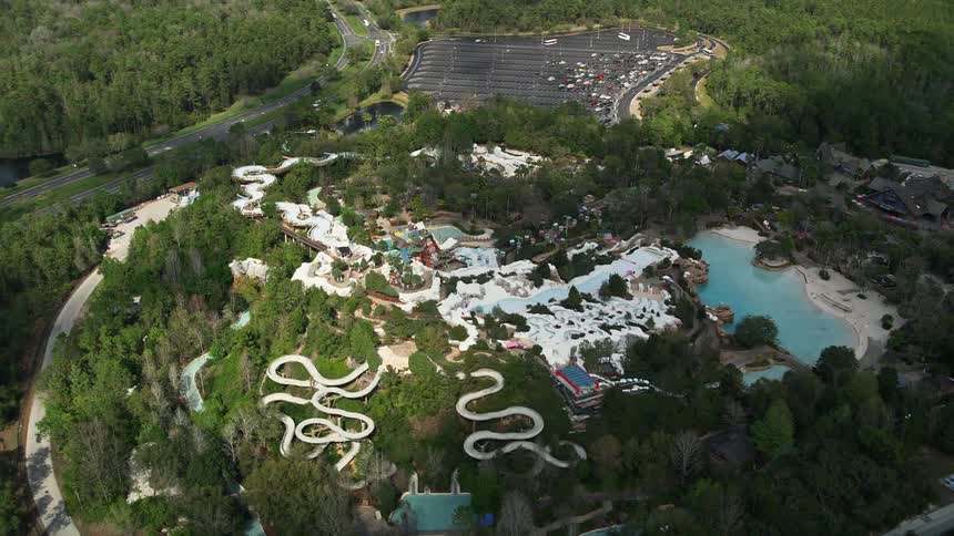 A breathtaking aerial view of the world-renowned Disneys Blizzard Beach water park with exciting water slides pools and a parking lot captured during a partly cloudy summer day in Florida