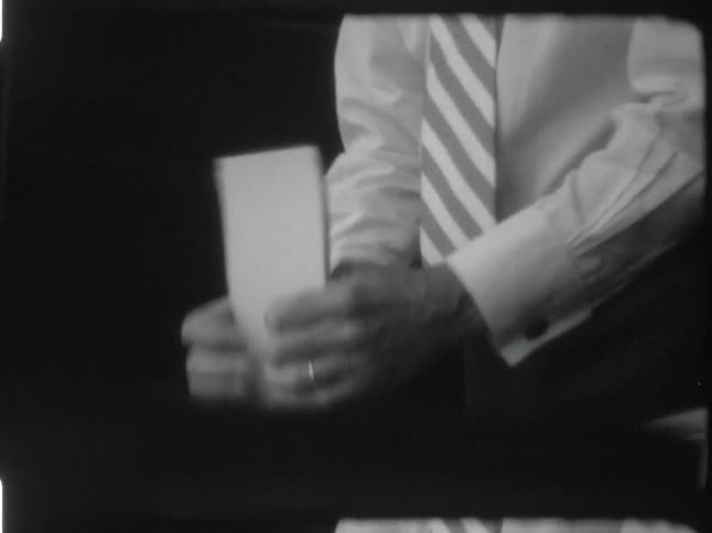 Elderly man wearing a shirt and tie organizing papers in front of him