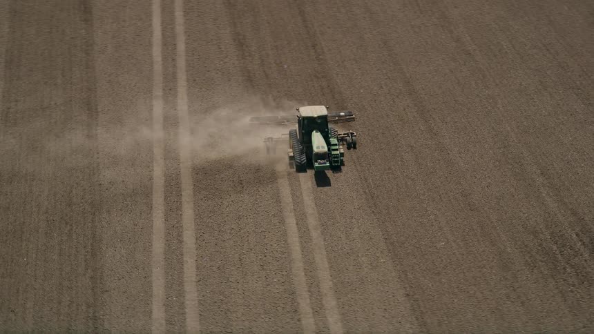 Aerial footage of a tractor tilling a brown farm field in Camarillo California