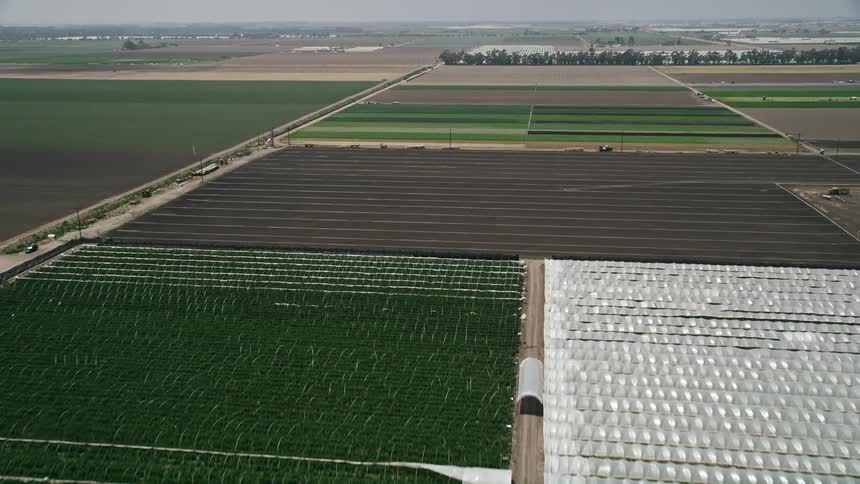 An aerial flyover of crop fields and greenhouses in Camarillo California showcasing the rural landscape of the Southern California province