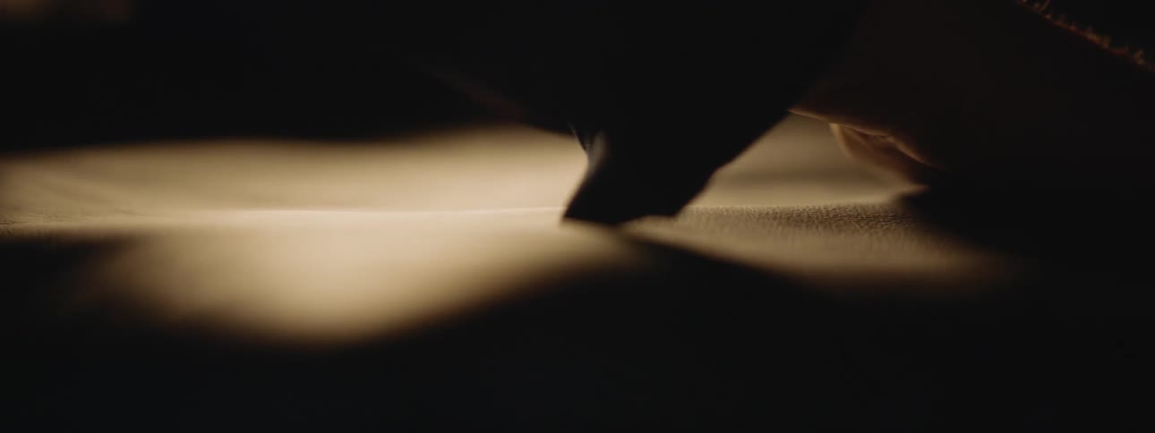 Close up of the hands of a craftsman using his hands to flatten a piece of leather over a table