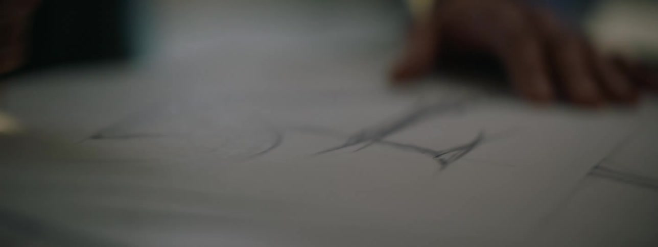 A close up of a person using a pencil to draw on a white paper on a table