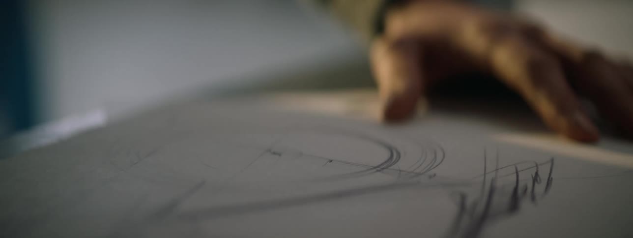 Person stands drawing in pencil on large piece of paper