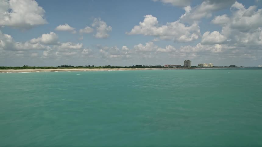 Aerial footage of the Florida coastline near Fort Pierce showing blue waters along the beach with partly cloudy skies in the background