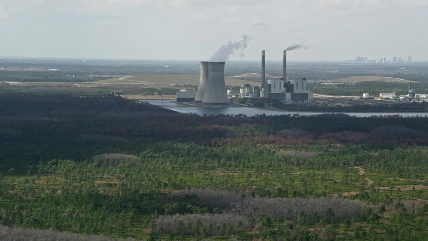 Approaching a coal fired power generation facility in Orlando Florida with billowing smoke seen from above during daytime
