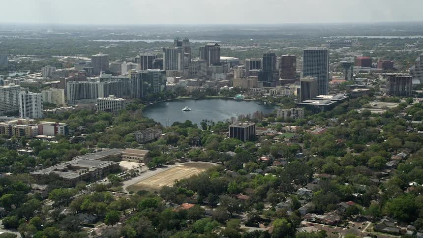 Stunning aerial footage of downtown Orlando with Lake Eola showcasing the central Florida skyline and shoreline on a sunny day