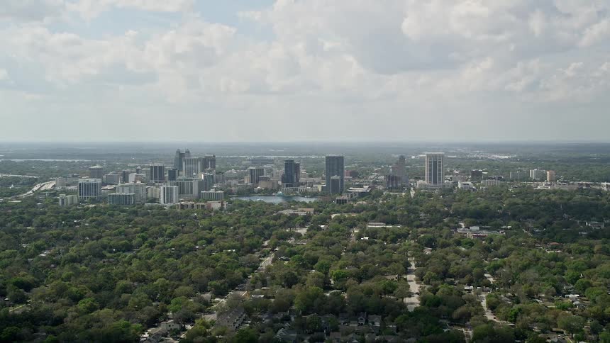 A stunning aerial view of downtown Orlando on a partly cloudy day featuring a lush green landscape and modern skyscrapers