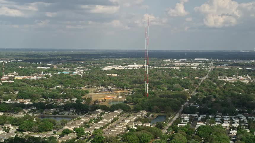 Aerial footage flyby of radio towers in Winter Garden Florida during daytime with partly cloudy skies