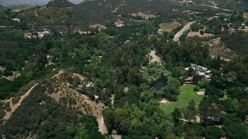 Aerial flyover of hillside mansions in Malibus countryside as seen from Kanan Dume Road during a sunny day