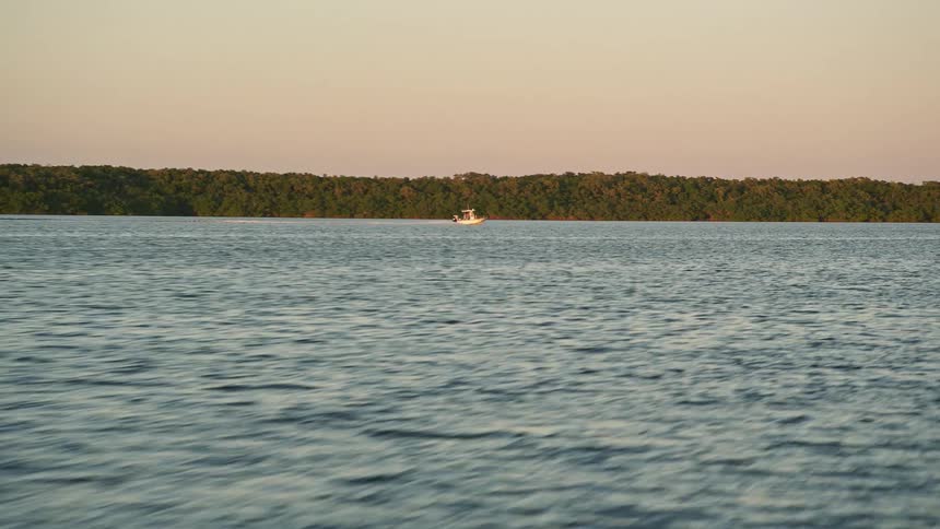 A fishing boat races past mangroves during sunset on the Key Largo shoreline in 5K aerial footage