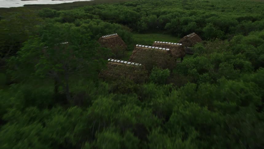 Flying low over the Florida Everglades marshland an aerial view reveals a hidden village of huts nestled in trees surrounded by wetlands and natural landmarks