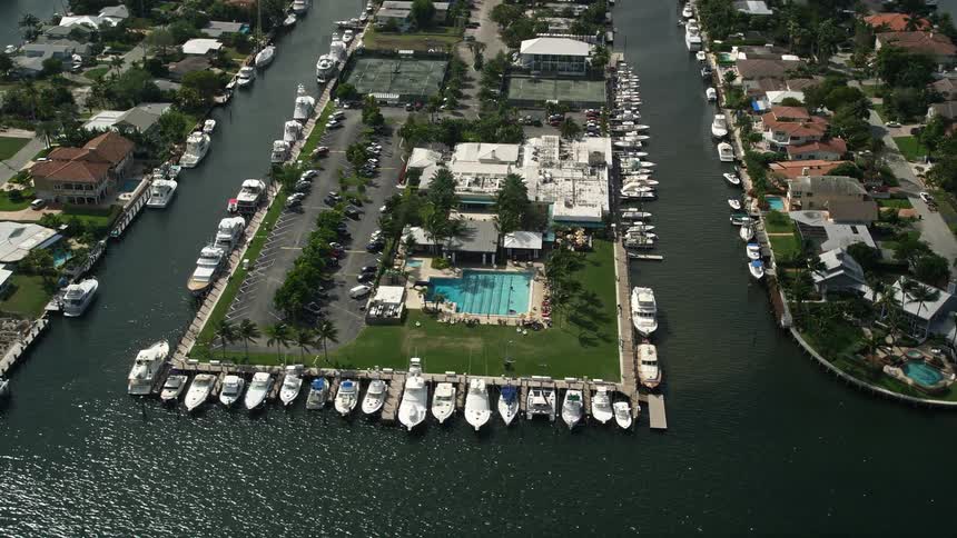 Aerial view of Lauderdale Yacht Club in Fort Lauderdale Florida with yachts and fishing boats making their way through the partly cloudy skies