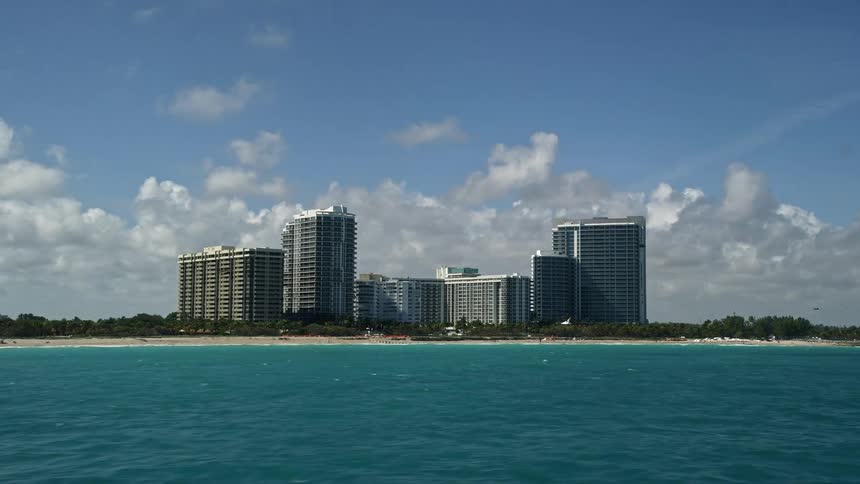 A stunning 5K aerial view of apartment buildings lining the picturesque shoreline of Bal Harbour Florida including the ONE Bal Harbour Resort and Spa