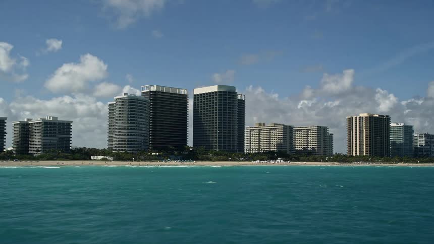 A breathtaking birds eye view of The St Regis Bal Harbour Resort and its surrounding coastal properties with people enjoying the sunshine and relaxation on the beach below