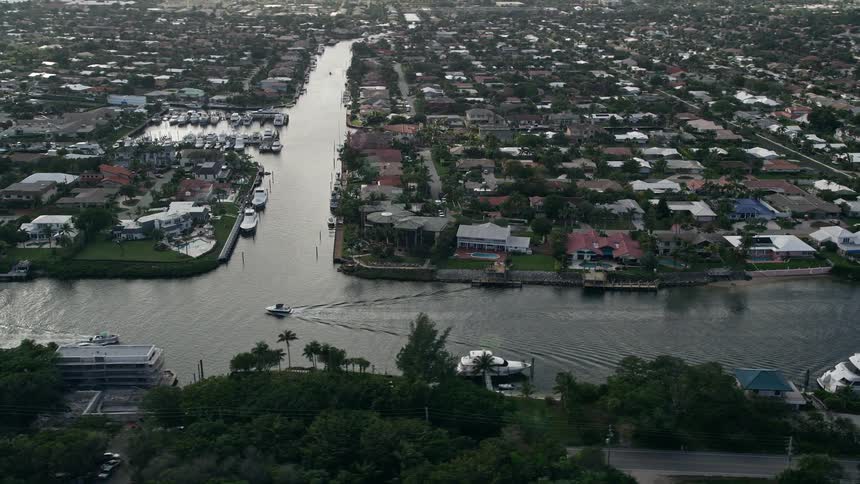 Aerial flyby of mansions neighborhoods and the Intracoastal Waterway in Lighthouse Point Florida with partly cloudy skies and waterfront properties