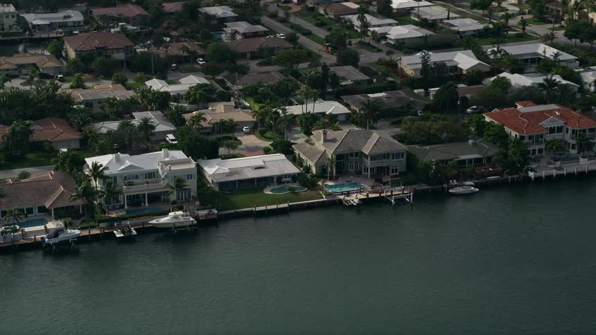 Flying over mansions along Intracoastal Waterway in Lighthouse Point Florida on a partly cloudy day