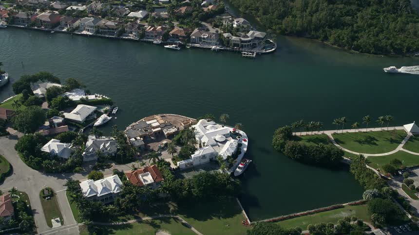 Aerial view of a mansion on the bank of Intracoastal Waterway as a boat passes by in Boca Raton Florida