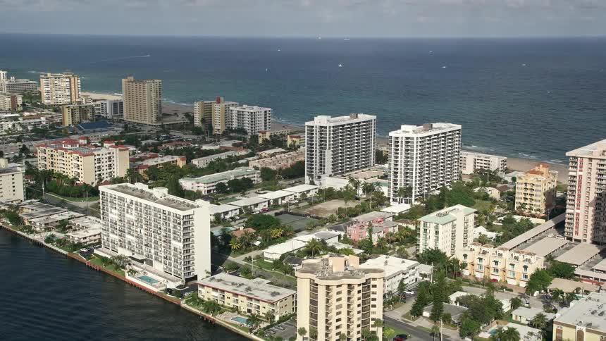 Flying over condominium complexes approaching the coastline of Pompano Beach FL with a grand view of the residential areas and condos