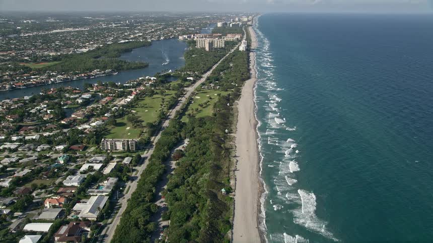 Aerial footage of flying by South Beach Park in Boca Raton Florida revealing the coastline and the beachgoers enjoying the sun and sand