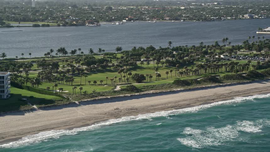 A beautiful aerial view of Palm Beach Par-3 Golf Course on the Florida coastline with a partly cloudy sky and palm trees in the background perfect for enjoyment relaxation and recreation