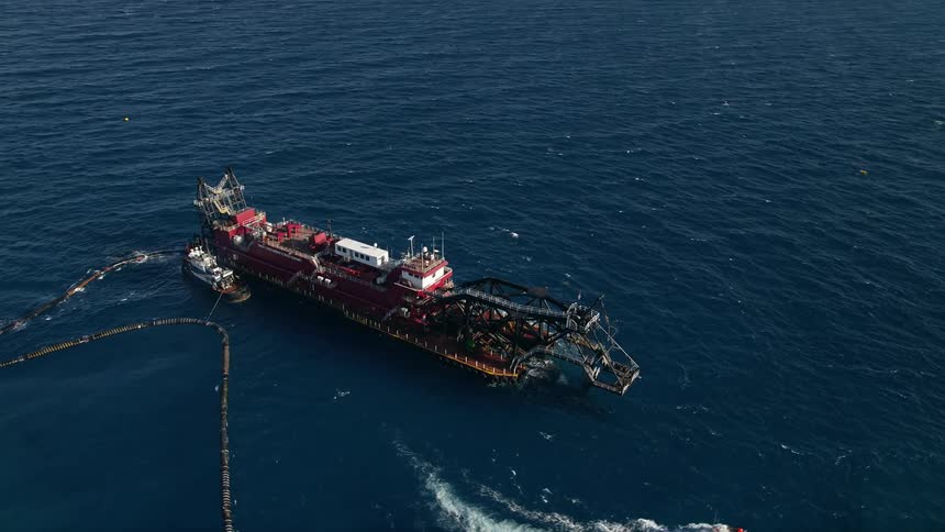 An aerial footage of a dredging ship approaching and orbiting the coast of Palm Beach Shores Florida