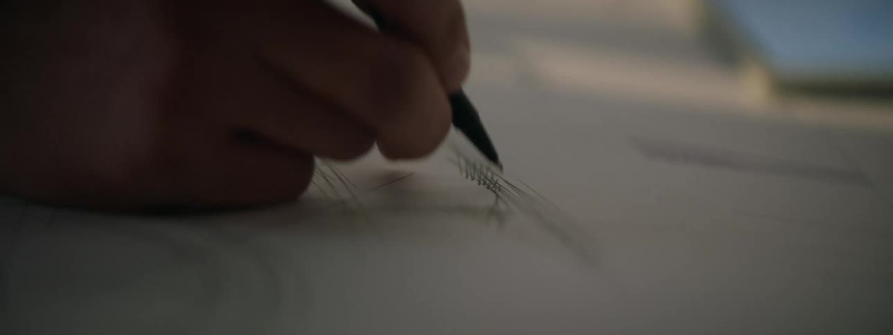 A man hurriedly draws a sketch on notebook paper