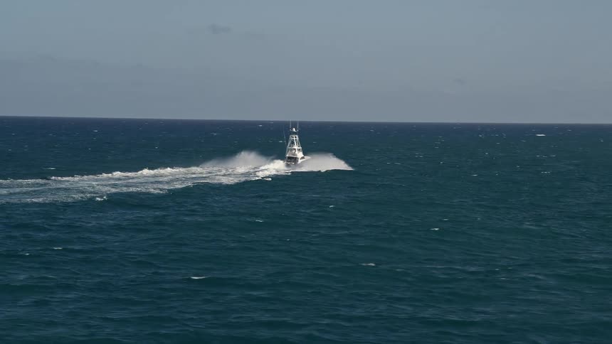 Aerial footage tracking a fishing boat sailing across the Atlantic ocean in Jupiter Florida on a partly cloudy day during spring or summer