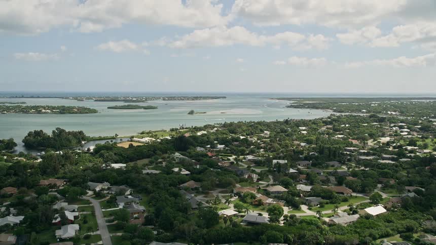 Flying over a coastal suburban neighborhood towards an inlet with water on the horizon in Stuart Florida during the daytime
