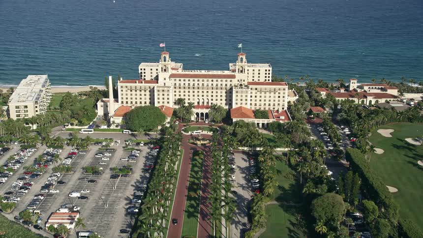 A breathtaking aerial view of Breakers Ocean Golf Course and The Breakers Palm Beach in Palm Beach Florida during the summer with partly cloudy skies and cars driving by the resort on the coast